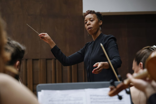 black woman holding a conductor's baton leading an orchestra